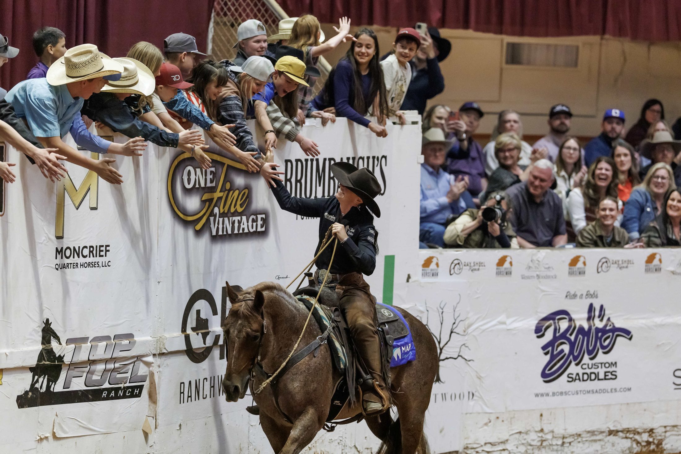 Erin Taormino high-fiving young fans from the back of Hazardouz Material after winning the 2025 World's Greatest Horseman